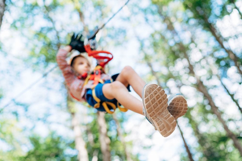 Boy descends the zip line while sitting on the safety belt. High quality photo