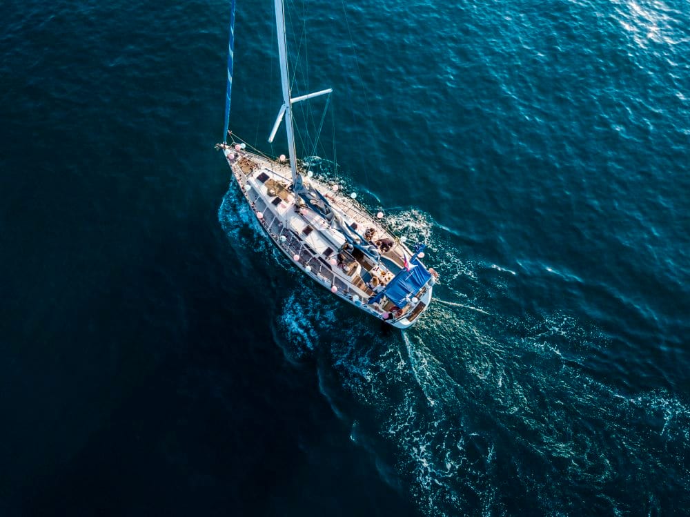 overhead top aerial view of luxury sail boat in the crystal clear blue sea water lagoon