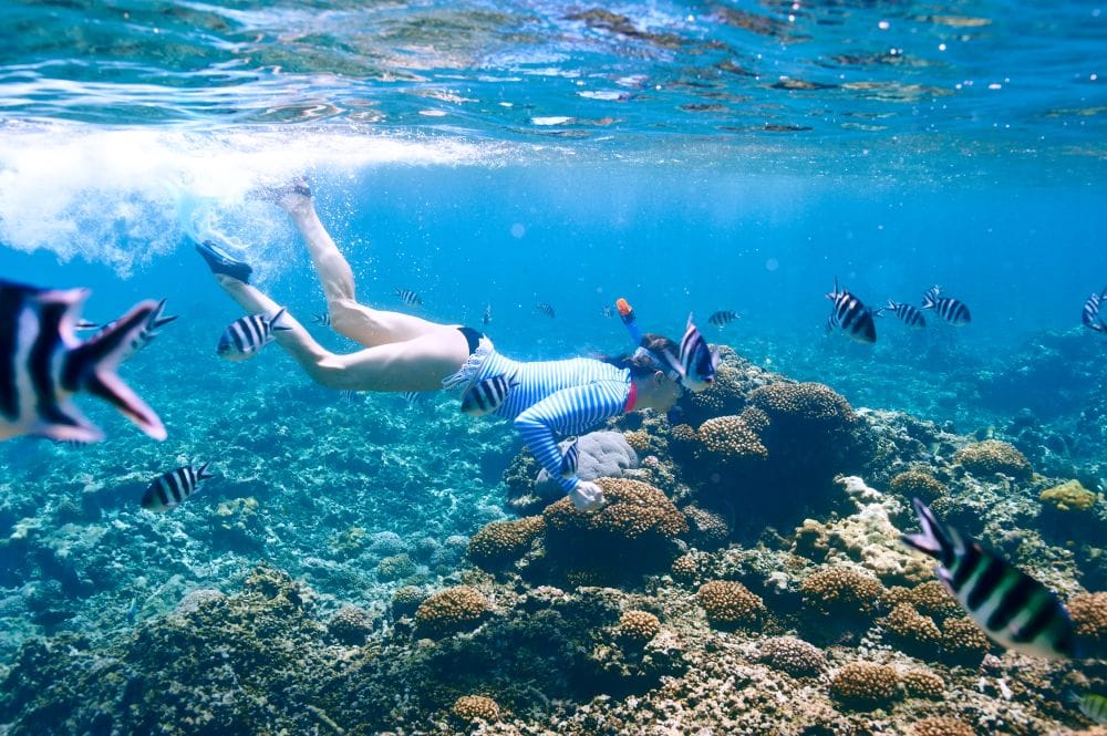 Woman with mask snorkeling in clear water